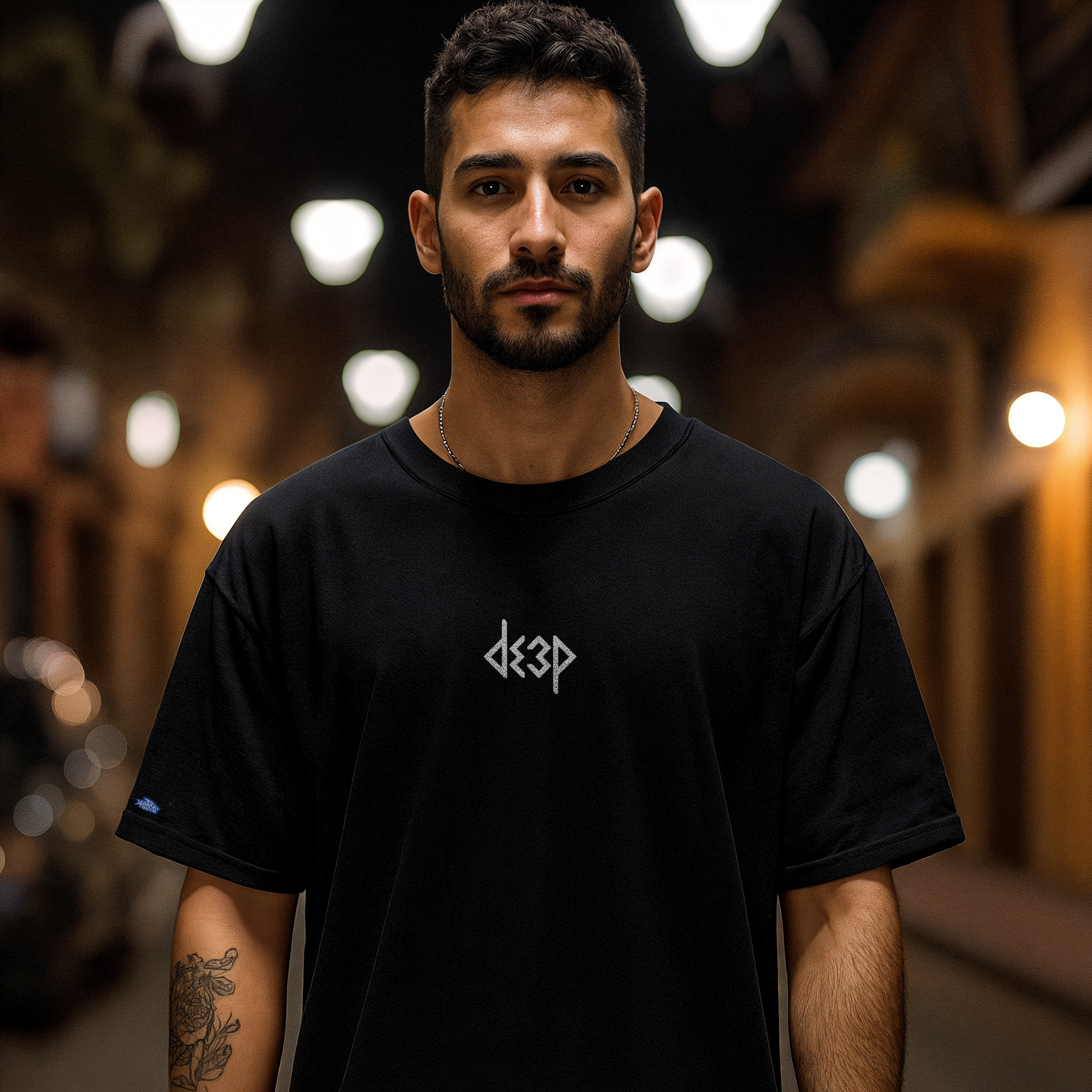 Modelo luciendo la playera TRION DE3P Oversize de algodón negro, con el logo de DE3P en blanco en el pecho.